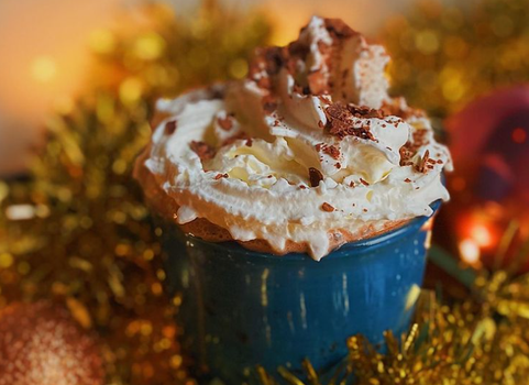 hot chocolate in blue mug with whipped cream on top and chocolate sprinkles