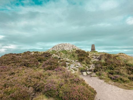 Tick Nock Walk with heather bushes, a cloudy blue sky and the well known fairy castle