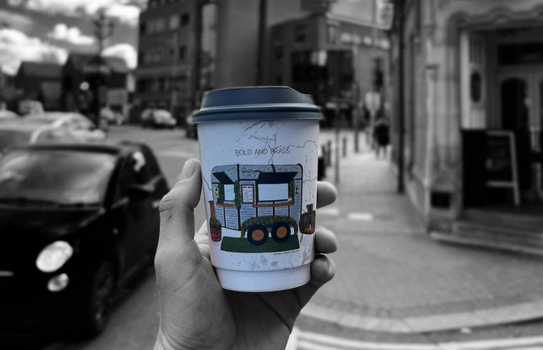 Bold and Brass coffee cup. In the background is the main street in Rathmines in black and white