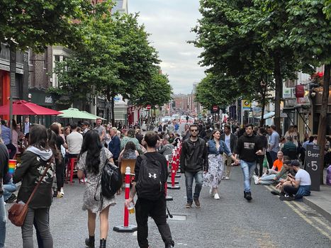 traffic-free parliament street in dublin with people walking around and sitting outside bars