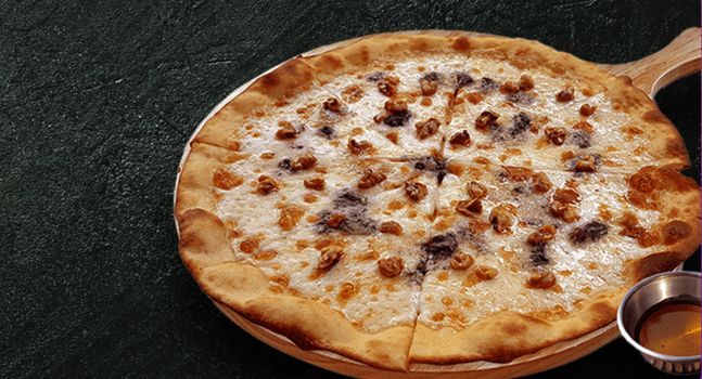 pizza on a wooden board with a small tub of sauce on the side